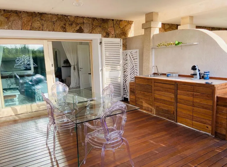 Patio con tavolo, sedie trasparenti e cucina esterna in legno